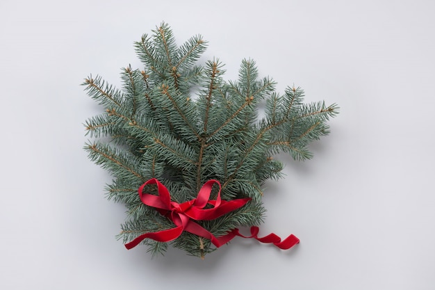 Christmas tree branches with red ribbon on grey. Xmas greeting card.