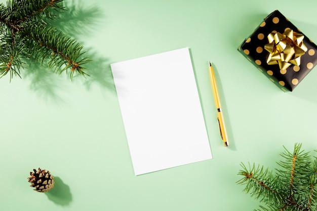 Christmas tree branches with shadows, white paper and pen for New Year's plans. Flat lay