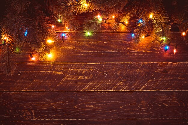 Рождественская елка и яркие огни лампочки. Счастливый рождественские (рождественские) фон. Старая текстура древесины - винтажные стили