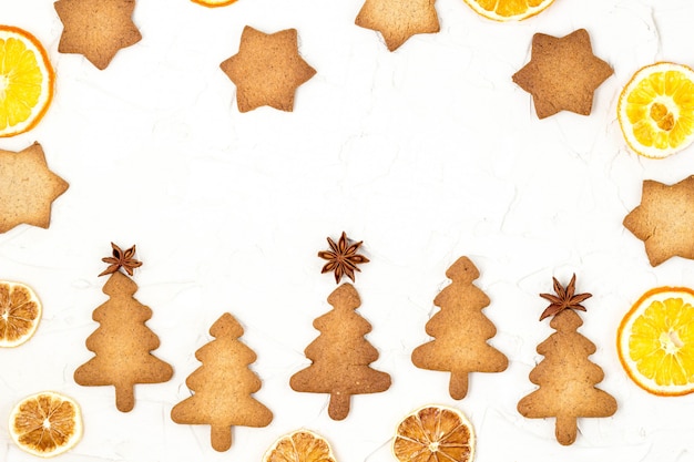 Christmas tree cookies with star toppers and dry orange on white background with copyspace.