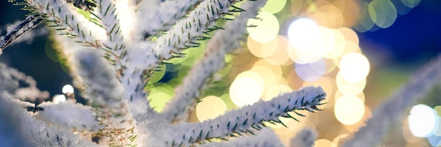 Christmas tree covered snow with yellow garlands lights and bokeh copy space with sparkled bokeh