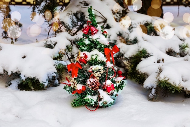 雪の下で冬の公園の新鮮な空気の中で花輪やおもちゃで飾られたクリスマスツリー