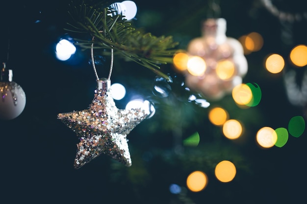 Украшение елки серебряной звездой и размытыми рождественскими огнями
