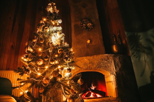 Photo christmas tree next to the fireplace. christmas decorations concept.