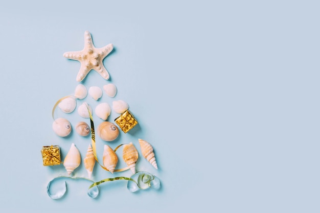 Фото Рождественская елка из морских ракушек альтернативная декорация синий фон новый год по морю рождество