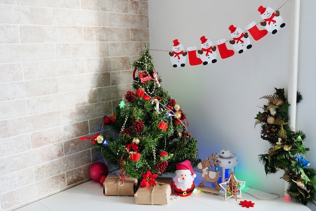 Albero di natale, regali e decorazioni a casa sul tavolo bianco in cucina