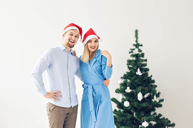 Albero di natale e concetto di feste - famiglia sorridente felice che porta i cappelli della santa che celebra a casa.