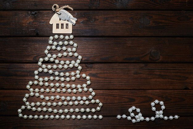 Christmas tree made of beads with the house with keys on the top on wooden background