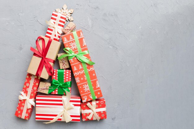 コピー スペースと新年のギフト ボックスの最小限の概念の上から色付きの背景ビューに美しく包まれたプレゼントで作られたクリスマス ツリー