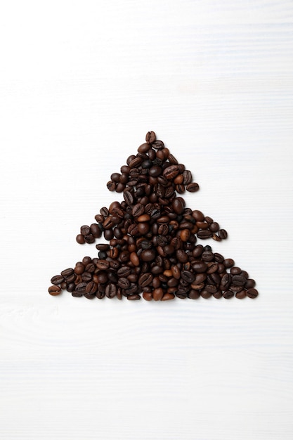 白い木製の背景にコーヒー豆で作られたクリスマス ツリー