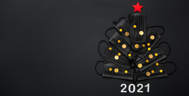 Foto albero di natale realizzato con maschere per il viso e coriandoli dorati con decorazioni festive. spazio della copia di capodanno 2021.