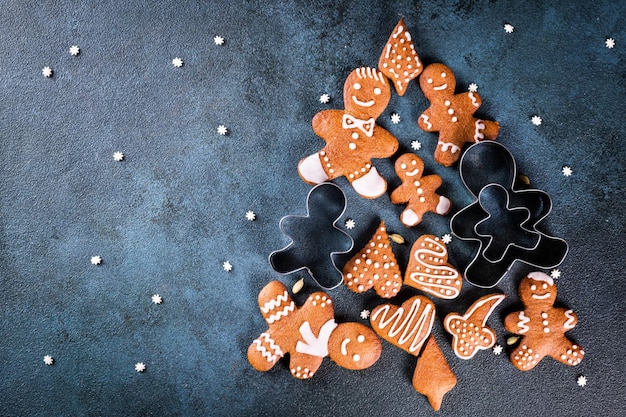 Christmas tree made from gingerbread cookies on dark blue background with copy space for text. Gingerbread cookie with kitchen utensils. new year and christmas postcard. Assorted cookies.