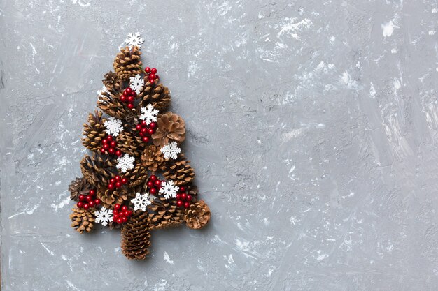 Christmas tree made from natural cones on colored background, view from above. New Year minimal concept with copy space