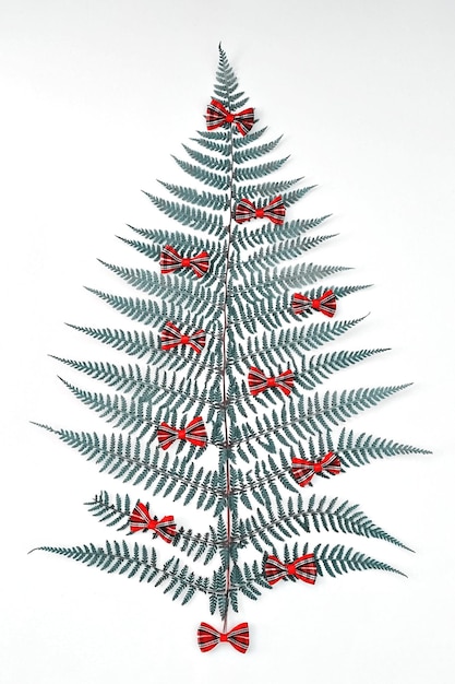 Christmas tree made from natural fern leaf decorative ribbon bows on white background, flat lay