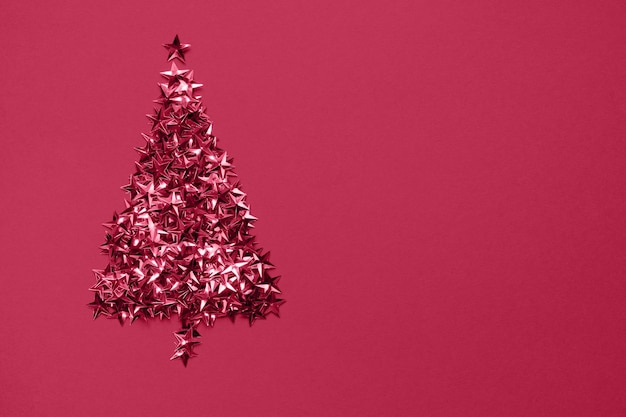 Christmas tree made of golden stars glitter confetti on red background Xmas holiday backdrop