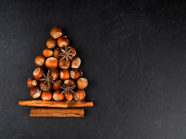 Christmas tree made of nuts, spices and dried oranges on black background