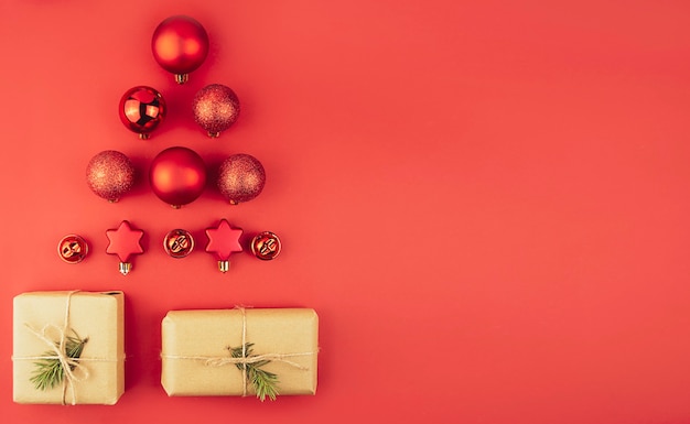 Christmas tree made of red Christmas balls gift boxes on a red background.Flat lay.Banner.Copy space