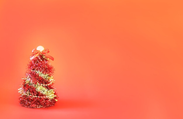 Christmas tree made of shiny bright decorative garland on red paper background