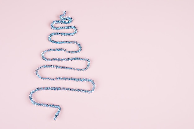 Christmas tree made of silver tinsel on pastel pink surface with copy space. Creative composition. Minimal New year concept. High quality photo