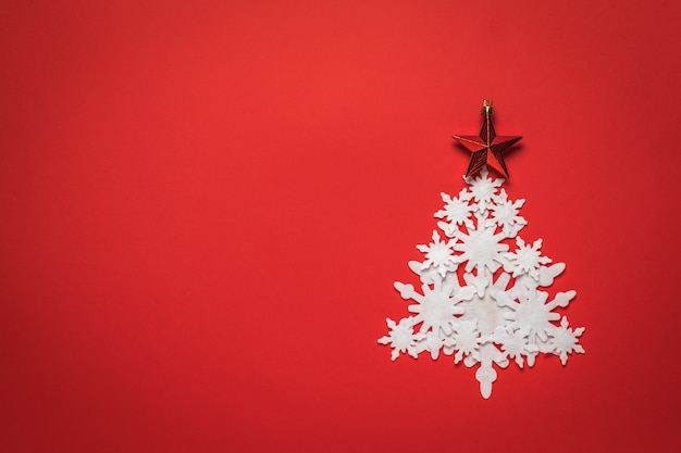 Christmas tree made of white paper snowflakes with a red star on a red background.