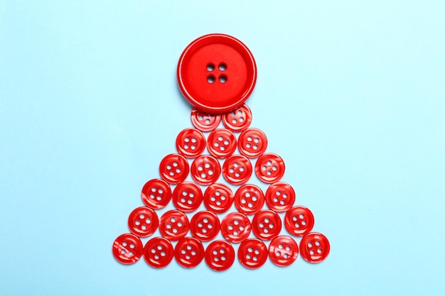 Christmas tree made with red buttons on light blue background flat lay