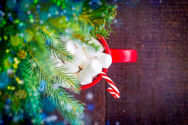 Christmas tree and mug with hot chocolate and marshmallows on wooden table