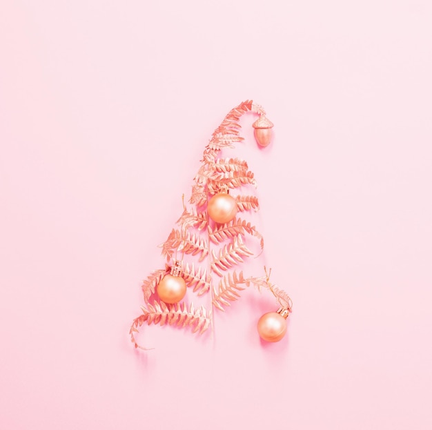 Christmas tree of painted golden leaves fern on pink paper background