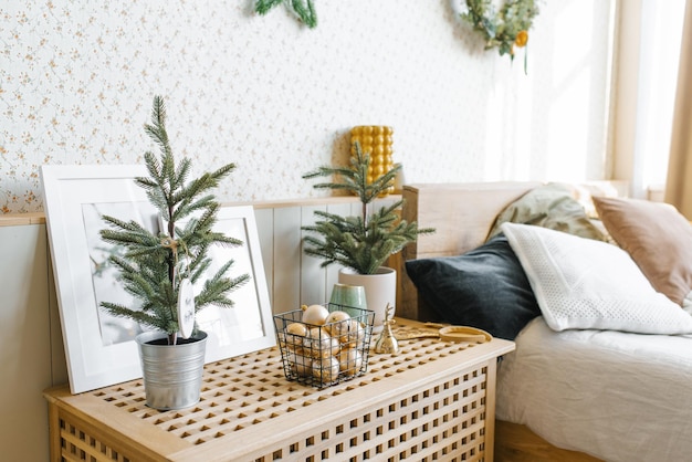 Foto albero di natale in una pentola sul comodino accanto al letto nella camera da letto