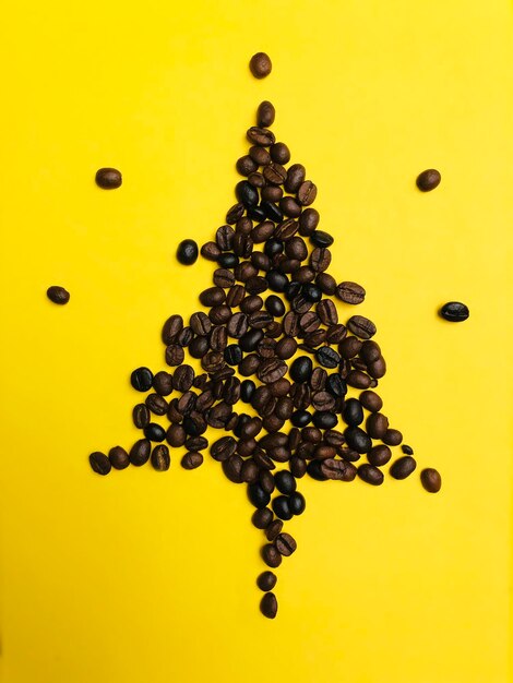 Christmas tree roasted coffee beans brown color on yellow background