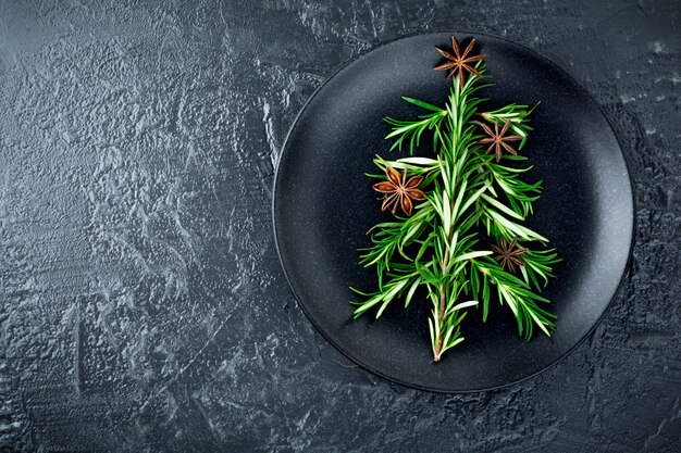 Christmas tree of rosemary and anise on a black plate background