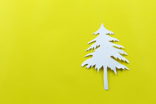 Christmas tree shape of white paper on yellow paper background.