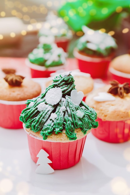 크리스마스 조명과 축제 배경에 눈이 뿌려진 크리스마스 트리 모양의 컵케이크 가족을 위한 크리스마스 트리트먼트 요리