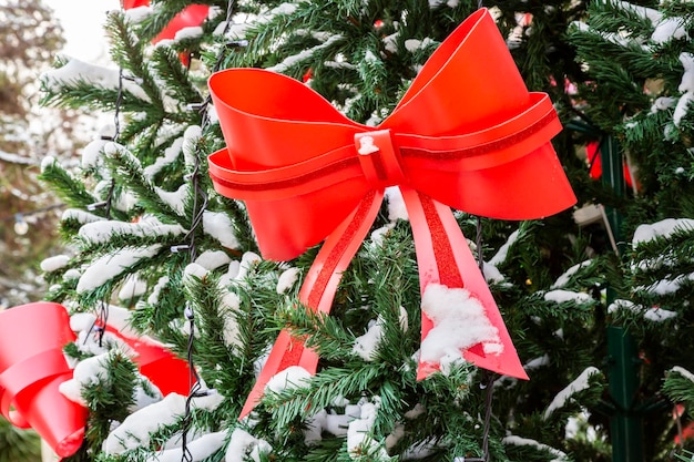 大きな赤い弓とぼやけた背景と雪の中のクリスマス ツリー クリスマスのための街のコンセプト通りの装飾