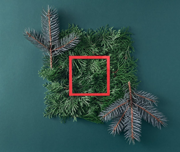 Albero di natale e rami di thuja con cornice di carta rossa su sfondo verde. concetto di nuovo anno.