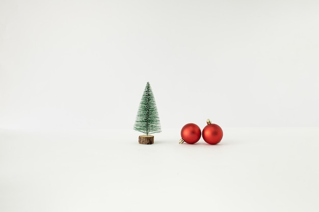 Christmas tree and two red baubles on white background Minimal New Year concept