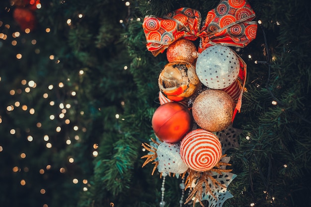 写真 木の上の光とボールの装飾が施されたクリスマスツリー。クリスマスと年末年始の背景。ヴィンテージカラートーン。クローズアップショット。