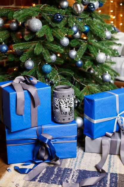 Christmas tree with blue and silver gifts in a white Christmas room. Nicely decorated house with silver and blue tree and gifts for Christmas.