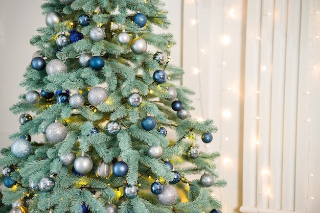 파란색과 은색 장난감이 있는 크리스마스 트리 새해의 상징으로 화환으로 장식된 크리스마스 트리