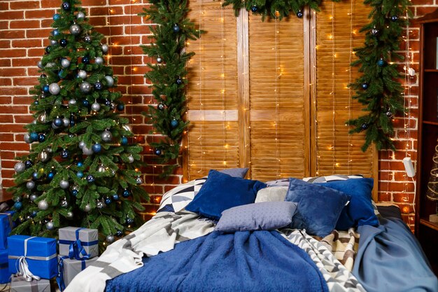 Christmas tree with blue toys in the bedroom. Beautifully decorated house for the new year with tree and bed decorations