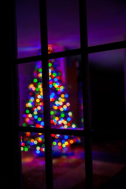 Photo christmas tree with color bokeh lights through a window.