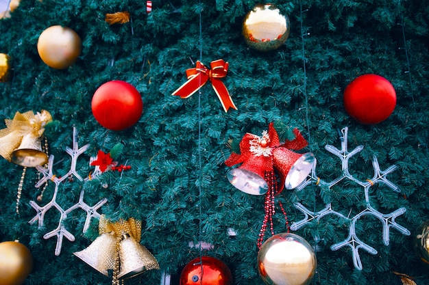 Фото Елка с праздничными украшениями из ленты снежинки, красных колокольчиков и шариков на зеленых еловых ветках б ...