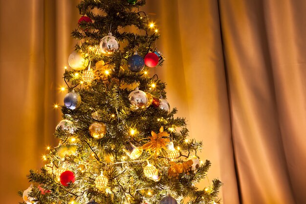 花輪と家の装飾が施されたクリスマスツリー。装飾的でお祝いの緑の木