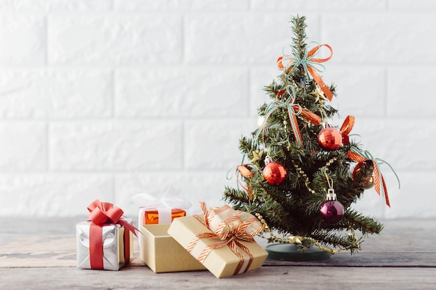 Рождественская елка с подарочной коробкой на деревянный стол