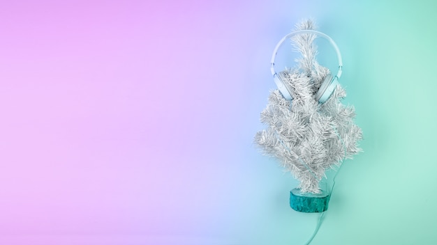パステルピンクブルーの背景の上にヘッドフォンとクリスマスツリー