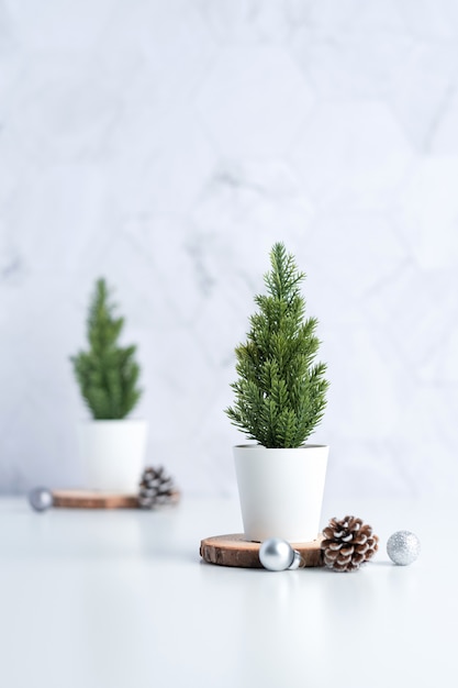 Photo christmas tree with pine cone,decor xmas ball on wood log at white table and marble tile wall