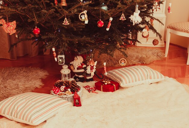산타 클로스 아래에 선물이 있는 크리스마스 트리와 두 개의 베개가 나란히 누워 있습니다.