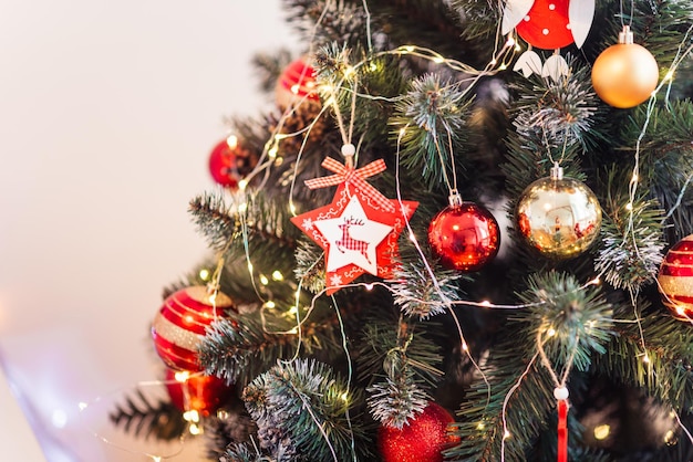 Фото Рождественская елка с красными и золотыми игрушками крупный план красная деревянная звезда с рождественским фоном оленей