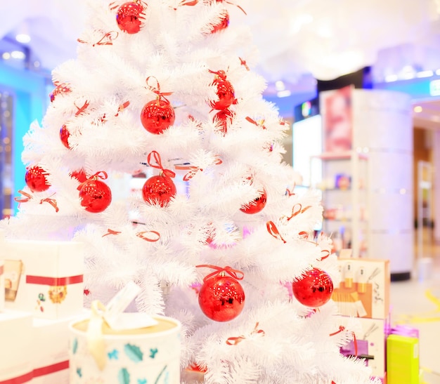 Christmas tree with red balls. Christmas tree with red balls. Concept New Year celebration background. White christmas tree decorated with red balls with colorful gift boxes