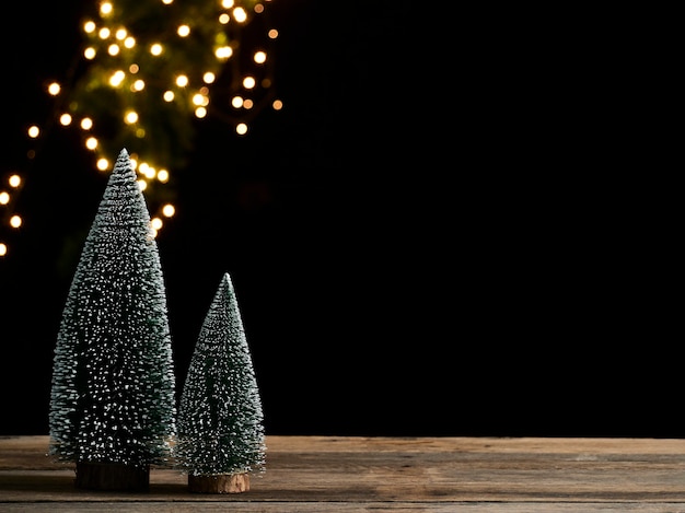 Christmas tree with snow on wooden table against dark background, bokeh effect, space for text