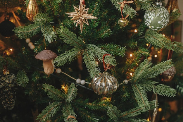 Albero di natale con palline vintage e luci dorate da vicino rami di albero di natale decorati in modo moderno con ornamenti eleganti nella sala festiva vacanze invernali preparazione tempo atmosferico